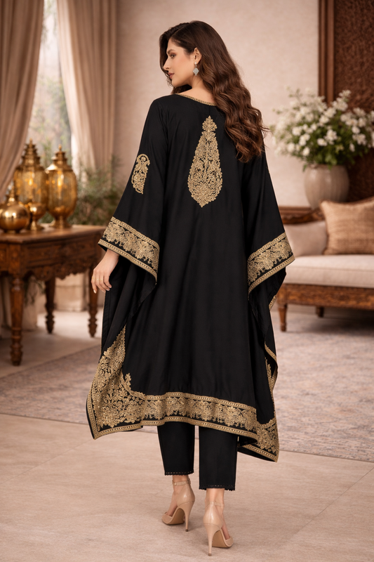Woman wearing a black outfit with gold embroidery in an elegant room.