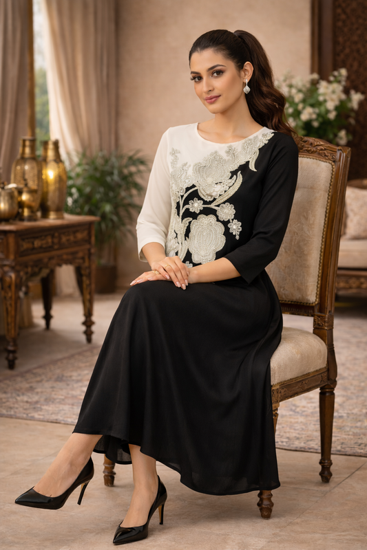Woman in a black and white dress sitting on a chair in an elegant room.