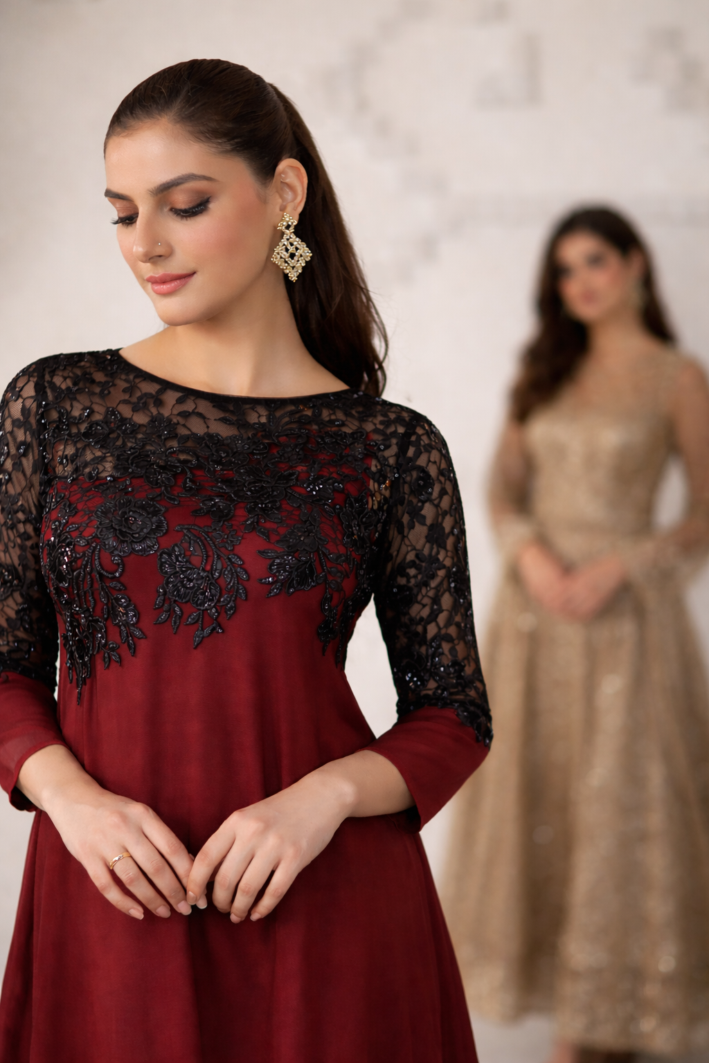 Woman wearing a red dress with black lace sleeves against a neutral background